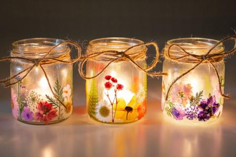three glossed glass jars with pressed flowers and lights inside
