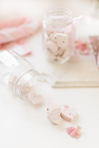 fallen over glass bottle with white heart-shaped shower steamers